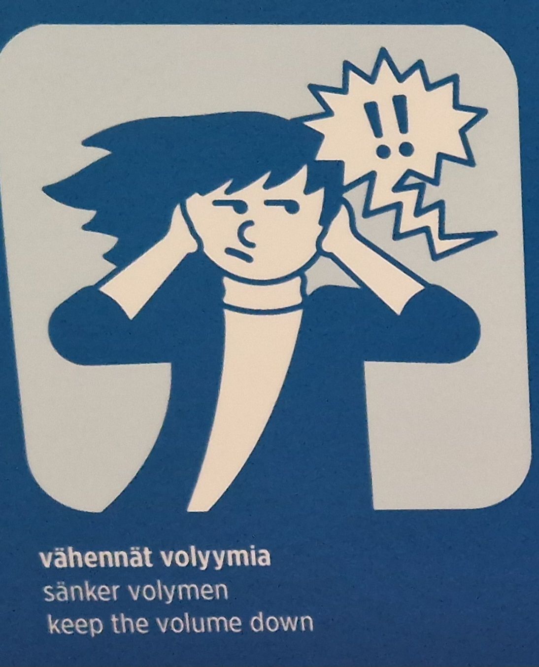 Hahmo pitelee tympääntyneenä korviaan, kun hänen päänsä vieressä näkyy rosoinen puhekupla, jossa on huutomerkkejä. Alla lukee teksti 'vähennät volyymia'.