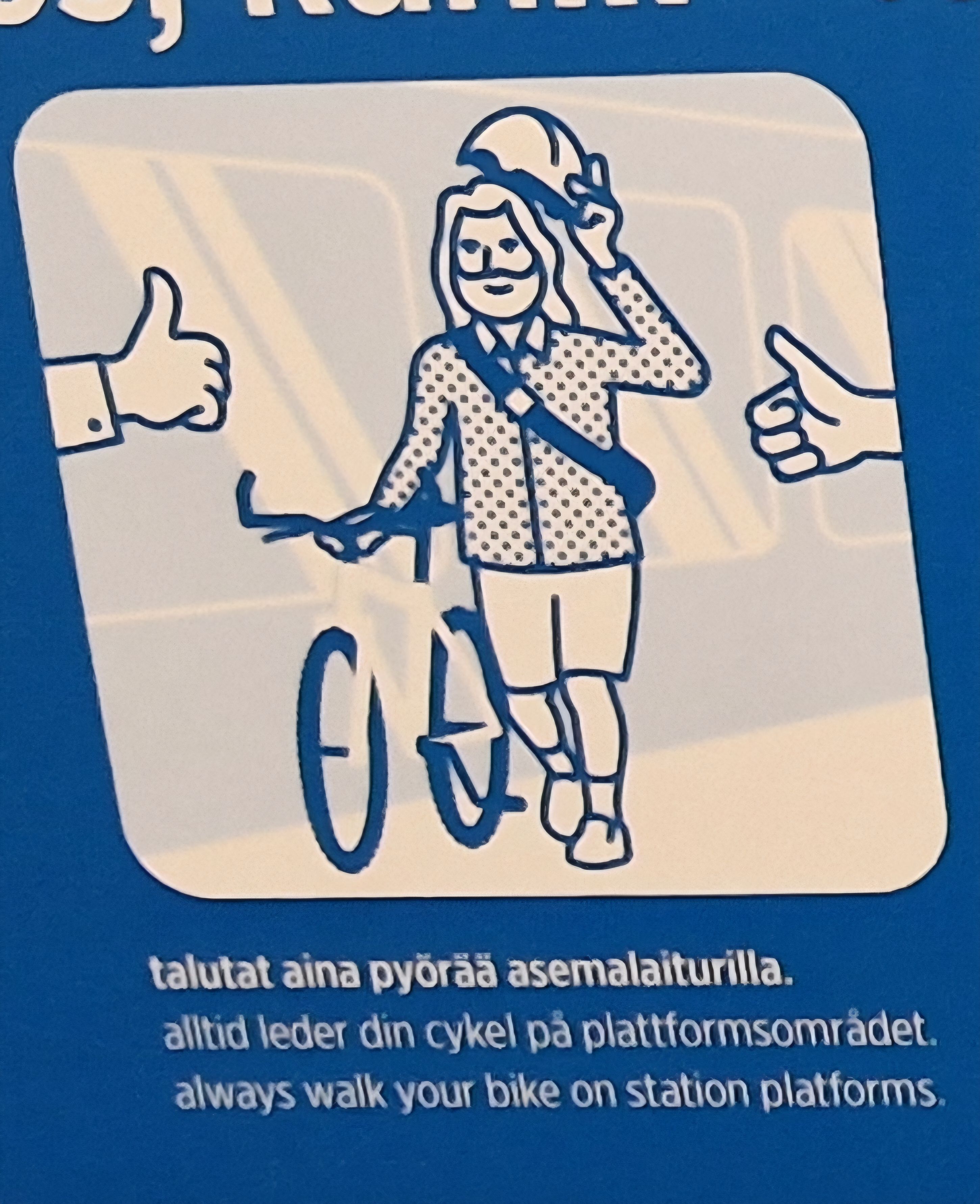 Pyörää taluttava ottaa kypärää päästään ja kävelee pitäen pyörästään kiinni. Kuvan molemmilla reunoilla näkyy peukkukädet. Alla lukee teksi 'talutat aina pyörää asemalaiturilla'.